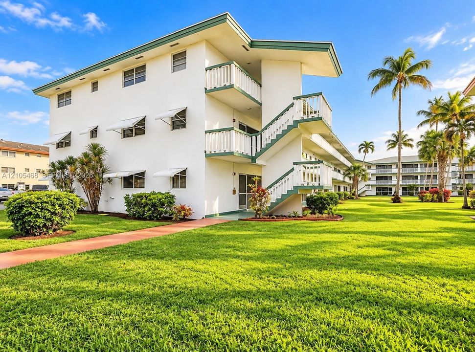 Multi-story building featuring white exterior, green trim, and white awnings