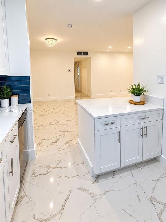 White shaker cabinetry, patterned tile flooring, blue subway tile backsplash, recessed lighting, and a kitchen island with stone countertop