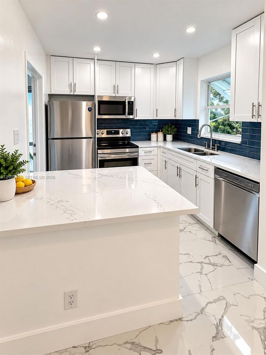 White cabinetry with stainless steel appliances, white countertops, and a dark blue subway tile backsplash