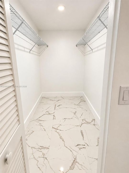Recessed ceiling light, white walls, wire shelving, marble-look floor tiles, and louvered bifold doors