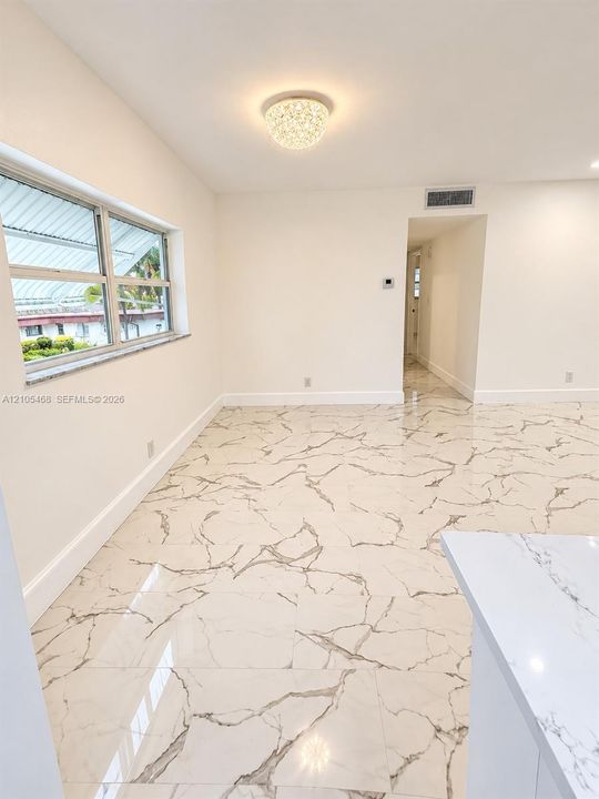 Recessed lighting, large format tile flooring, crown molding, double-pane window, and a decorative flush mount light fixture
