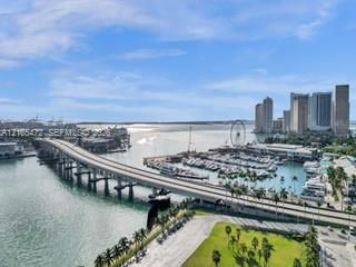 Waterfront cityscape featuring a marina, high-rise buildings, and a bridge