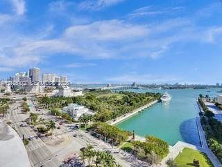 Expansive water feature, urban skyline, verdant landscape, visible roadways, distant bridge
