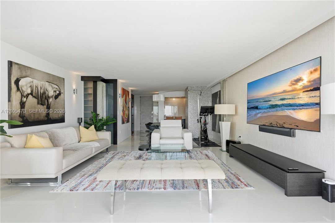 Recessed lighting illuminates the open-concept living space with white flooring