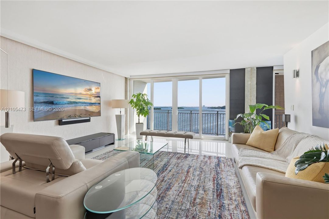 Expansive sliding glass doors, white tile flooring, recessed ceiling lighting, and wall-mounted sconces