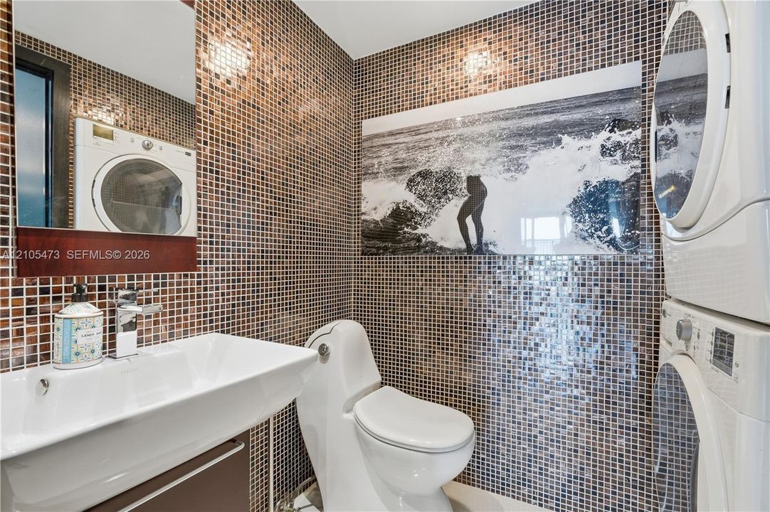Mosaic tiled walls with a white rectangular sink, chrome faucet, and built-in mirror