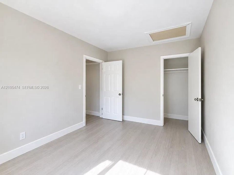 Light wood-finish flooring, neutral wall tones, white trim, and a ceiling access panel