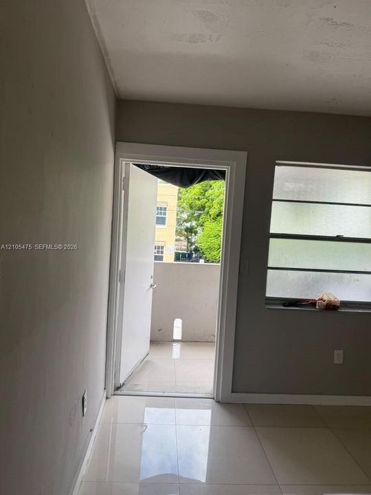 Interior space featuring large-format ceramic tile flooring, horizontal sliding windows, and a glass-panel door leading to an exterior balcony