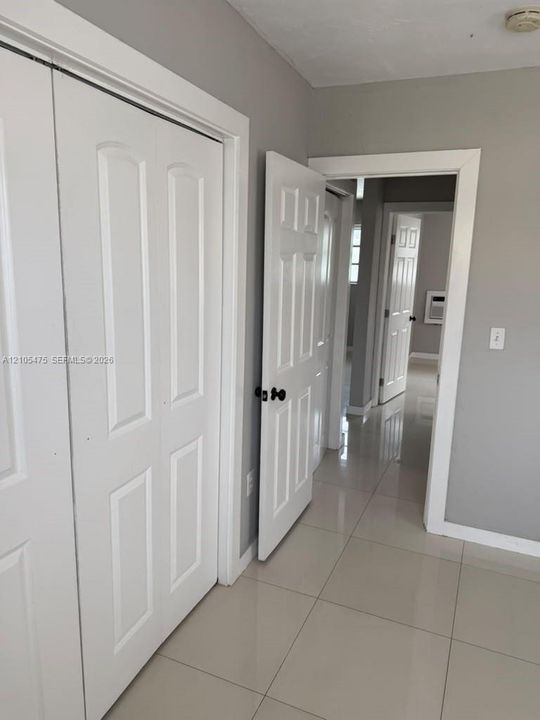 Large-format tile flooring, white six-panel doors with matte black hardware, and crisp white trim detailing