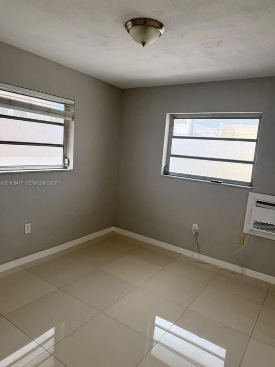 Room featuring neutral-toned walls, large-format polished tile flooring, two horizontal slider windows, and a flush-mount ceiling light fixture