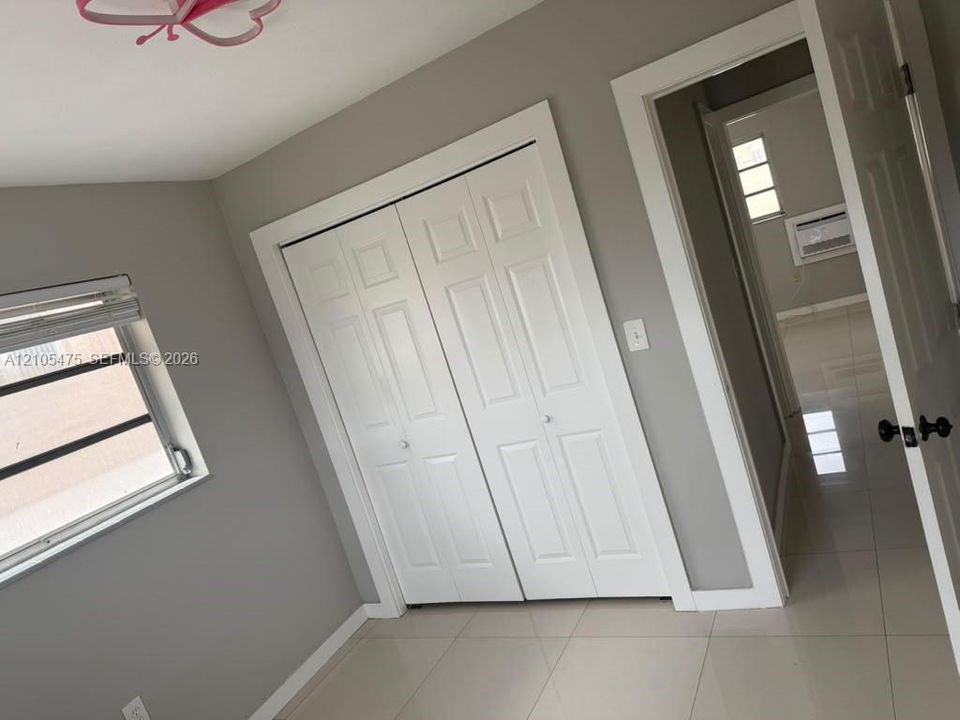 Interior space featuring neutral wall paint, polished tile flooring, white-finished interior doors, and a double-door closet with panel detailing