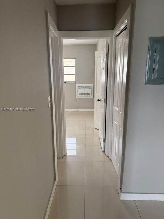 Interior hallway featuring polished tile flooring, white six-panel doors, and neutral wall paint
