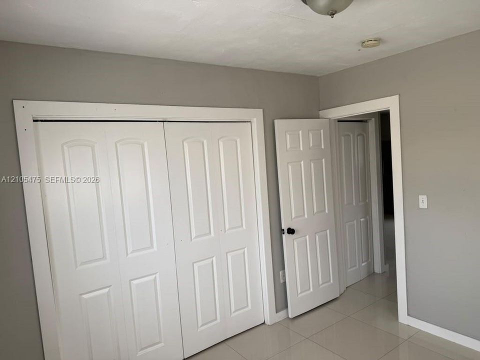 Neutral grey wall finish, white interior panel doors, and large-format tile flooring