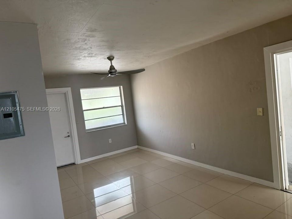 Interior space featuring large-format tile flooring, neutral wall paint, a multi-blade ceiling fan, and a horizontal louvered window