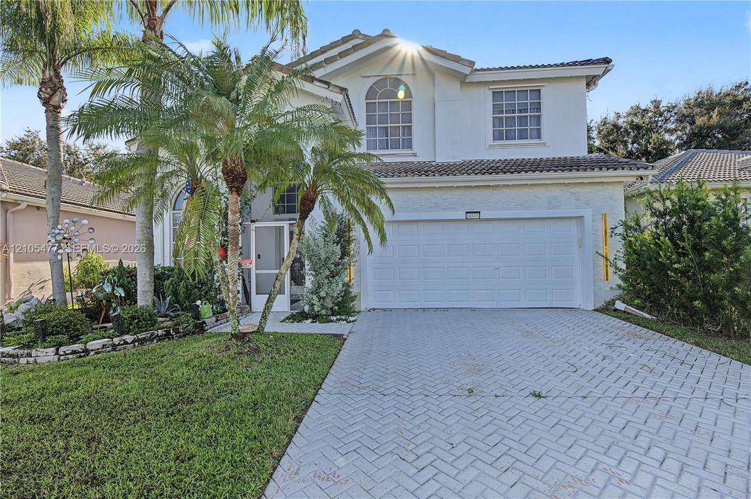 Two-story stucco exterior with a tiled roof, arched window, and a two-car garage