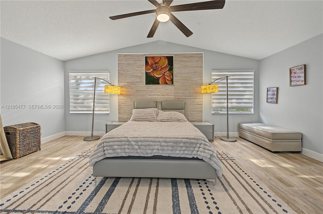 Vaulted ceiling with a ceiling fan, wood-finish flooring, and horizontal window blinds