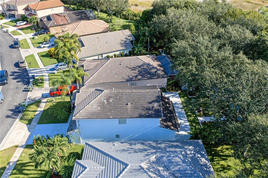 Property featuring a tile roof, mature landscaping, and a paved driveway