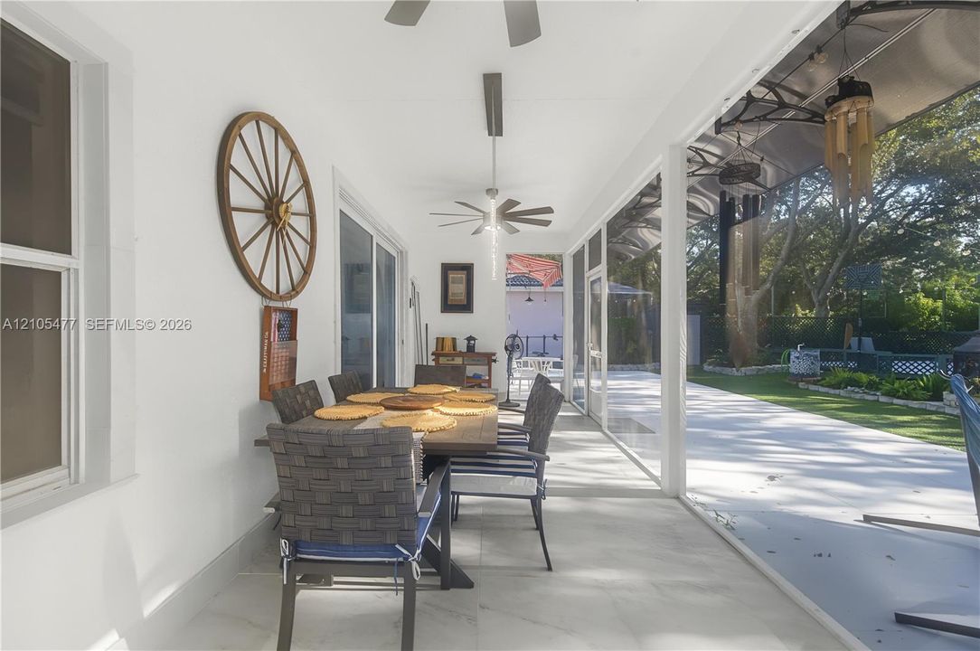 Screened patio with white walls, ceiling fans, and a tiled floor