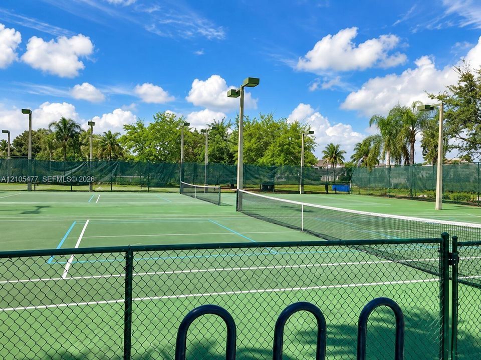 Hardcourt tennis courts with perimeter fencing and mature landscaping
