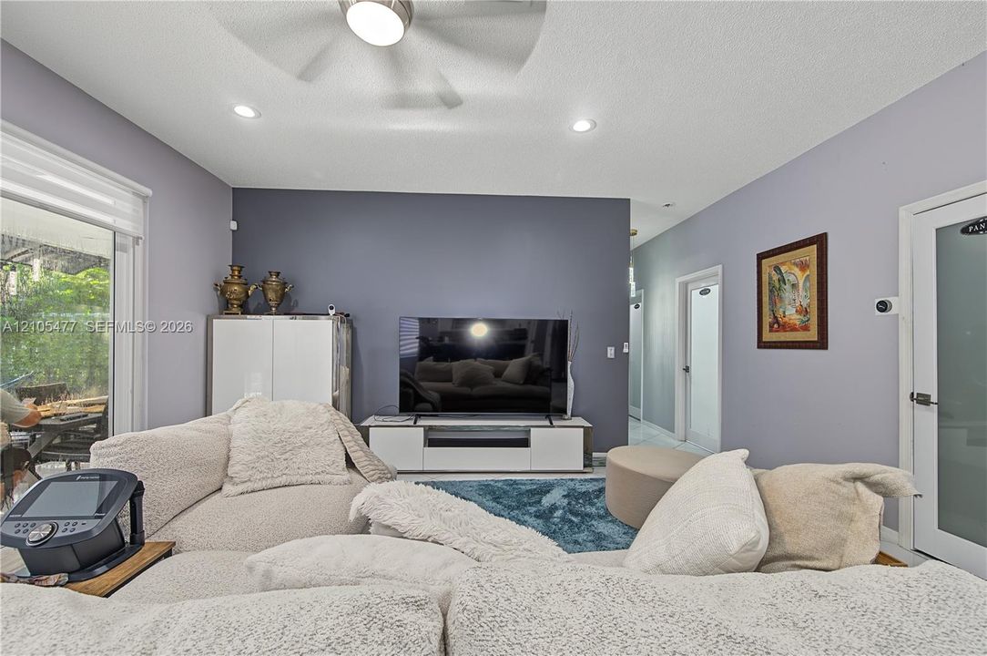Recessed lighting, ceiling fan, sliding glass door, interior doors with frosted glass panels, and a media console