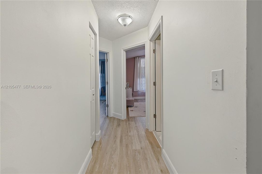 Hallway featuring wood-finish flooring, flush mount lighting, and white trim