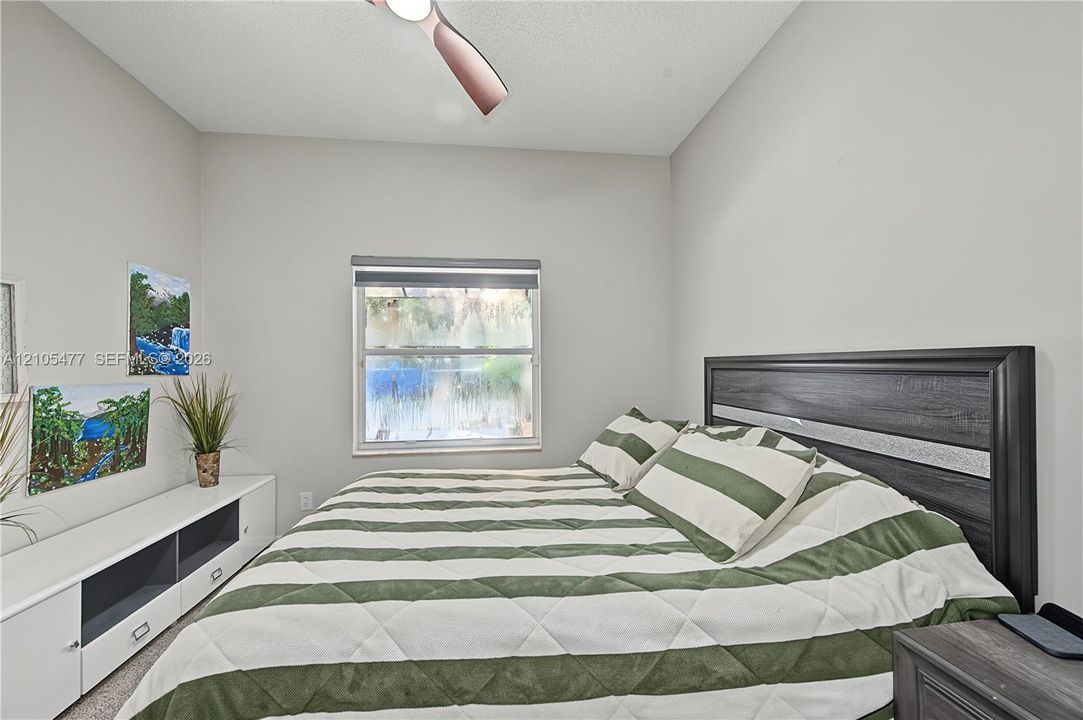 Well-lit room featuring a window with blinds, a ceiling fan, and light-colored walls