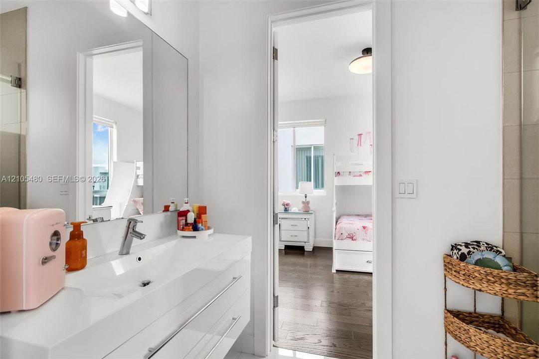 Bathroom featuring a single vanity with an integrated sink, polished chrome faucet, and expansive mirror