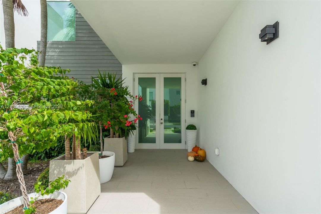 Covered entry featuring a light-toned concrete walkway, architectural wall sconces, and a modern double-door entry