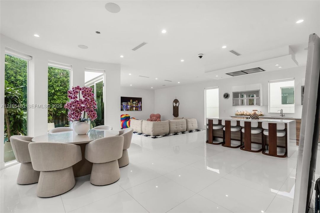 Spacious open-concept interior with polished tile flooring, recessed lighting, a kitchen island with seating, and large windows