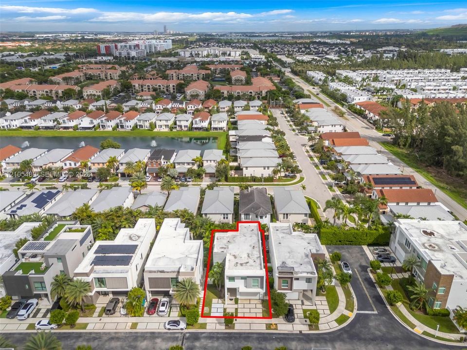 Aerial perspective of a multi-story residential property with a flat roof, situated in a community featuring varied architectural styles and established landscaping