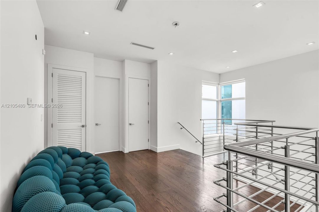 Hardwood flooring, recessed lighting, white walls, louvered door, and stainless steel railing