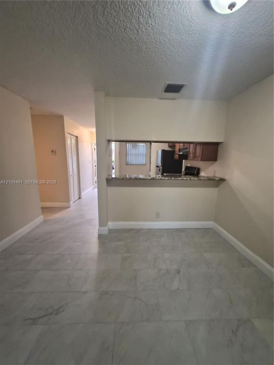 Porcelain tile flooring, neutral wall tones, pass-through window, wood cabinetry, and recessed lighting