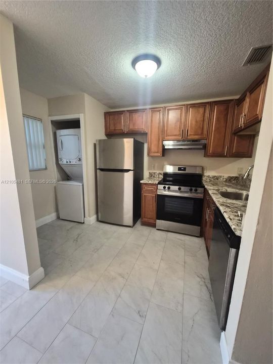 Kitchen featuring wood cabinetry, stainless steel appliances, and stone-finish countertops