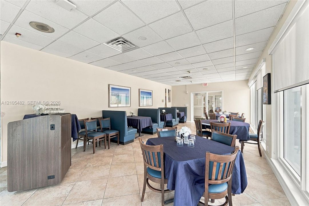 Spacious interior room featuring tile flooring, a drop ceiling with recessed lighting, and a large window wall with retractable shades