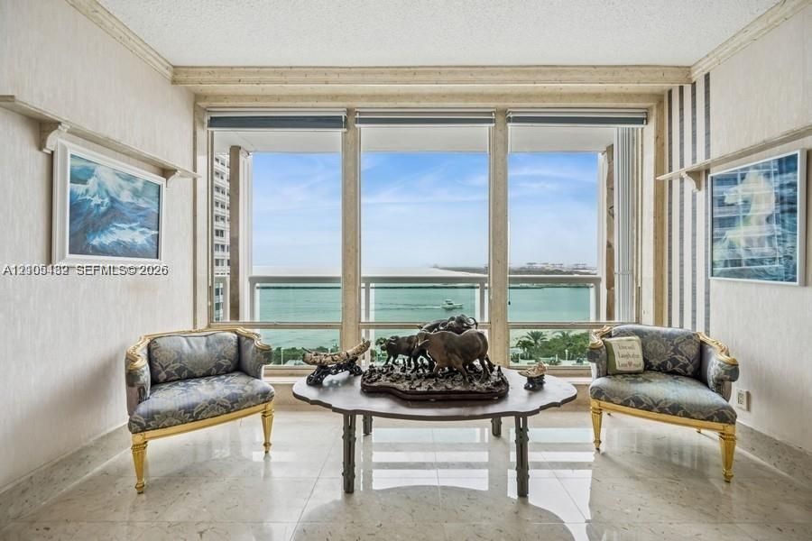 Floor-to-ceiling windows, polished stone flooring, custom wall molding, and direct water backdrop