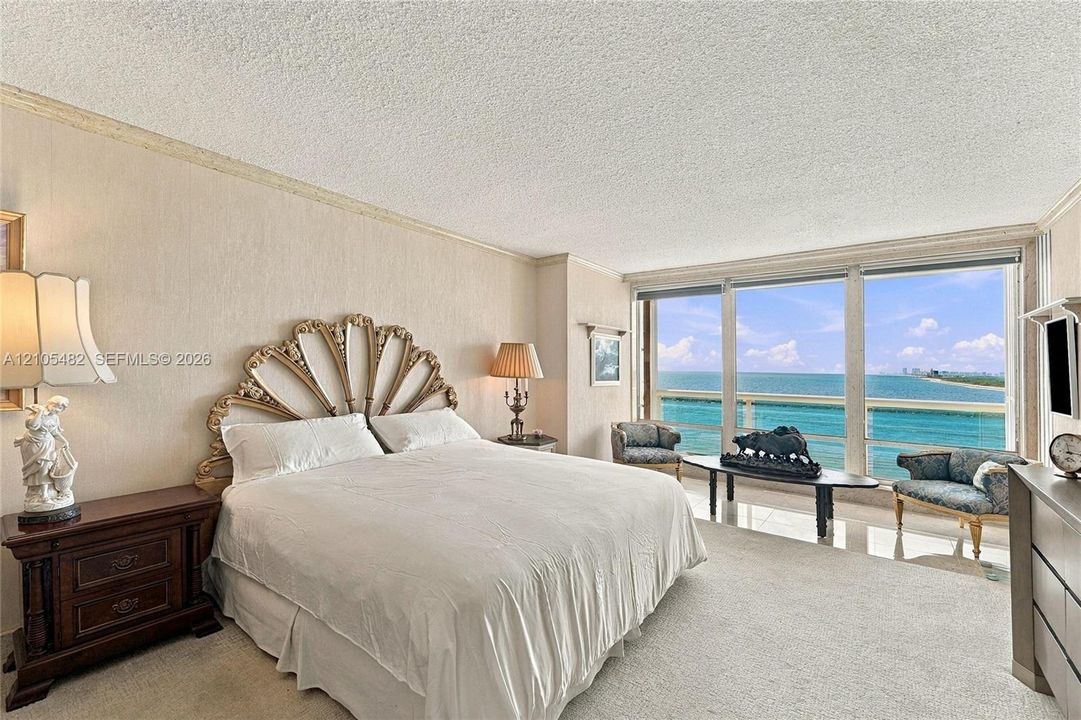 Floor-to-ceiling windows featuring ocean scenery, carpeted flooring, and wall-mounted crown molding
