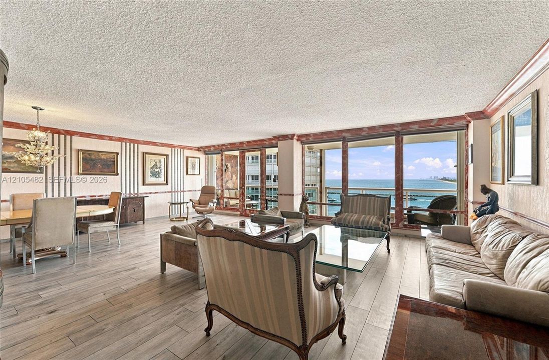 Living area featuring wood-finish flooring, full-height windows, and crown molding with stone-finish accents
