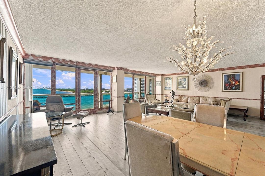 Open-concept living space featuring wood-finish flooring, floor-to-ceiling windows, and a decorative chandelier
