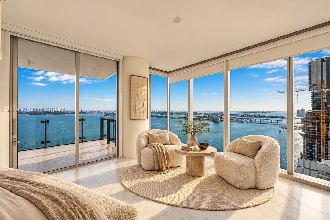 Floor-to-ceiling windows, wrap-around balcony with glass railing, stone-finish flooring, and expansive water scenery