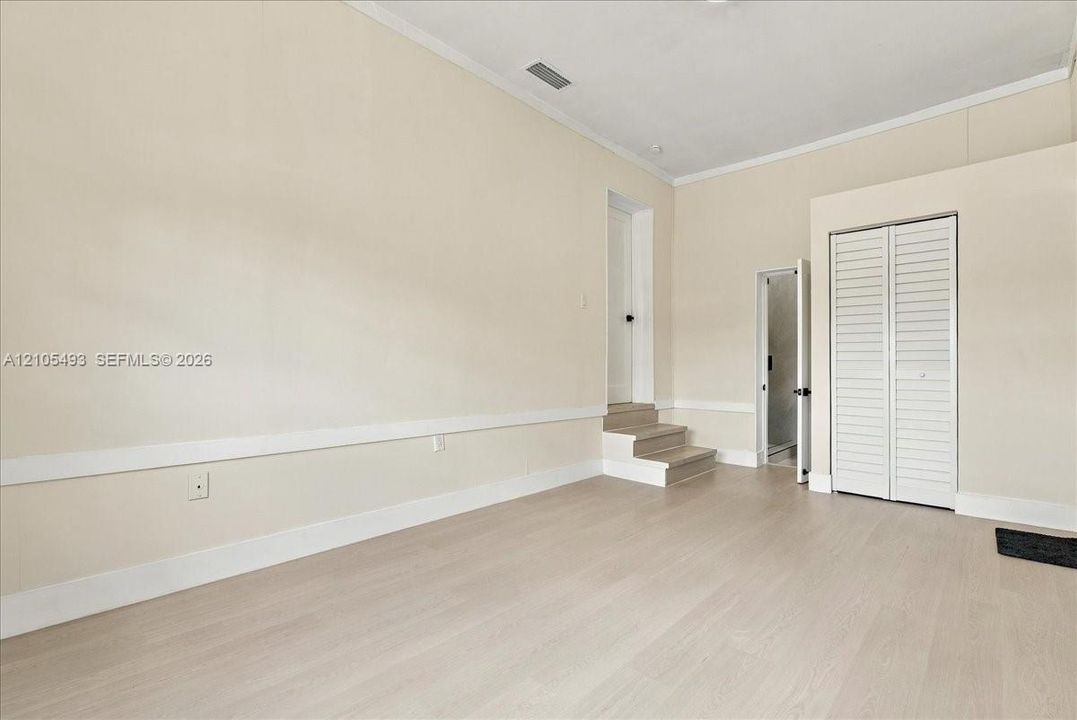 Interior space featuring wood-finish flooring, chair rail molding, louvered closet doors, and multi-level floor elevation