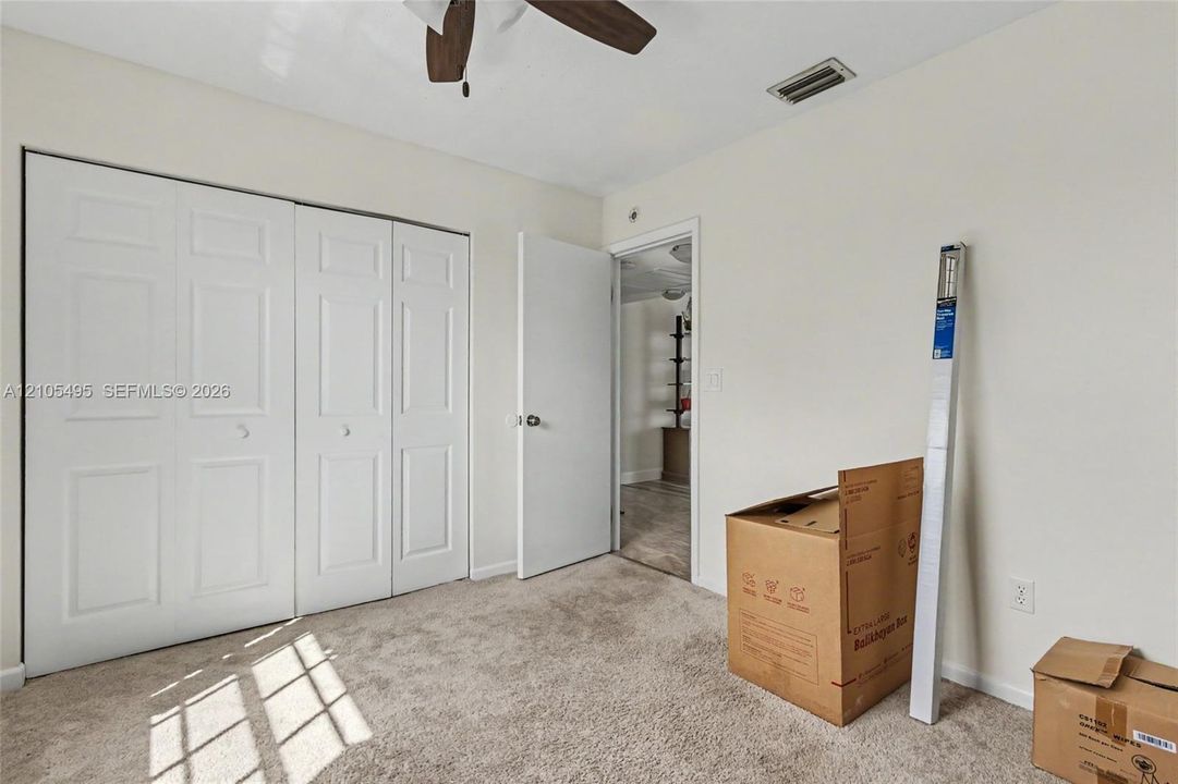Neutral-toned interior featuring wall-to-wall carpeting, bi-fold closet doors, and a ceiling fan