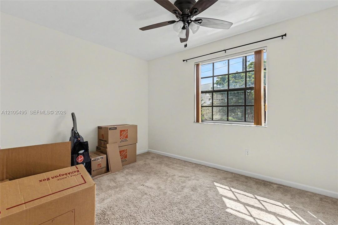 Room featuring wall-to-wall carpeting, a multi-pane window with a curtain rod, and a ceiling fan with integrated lighting