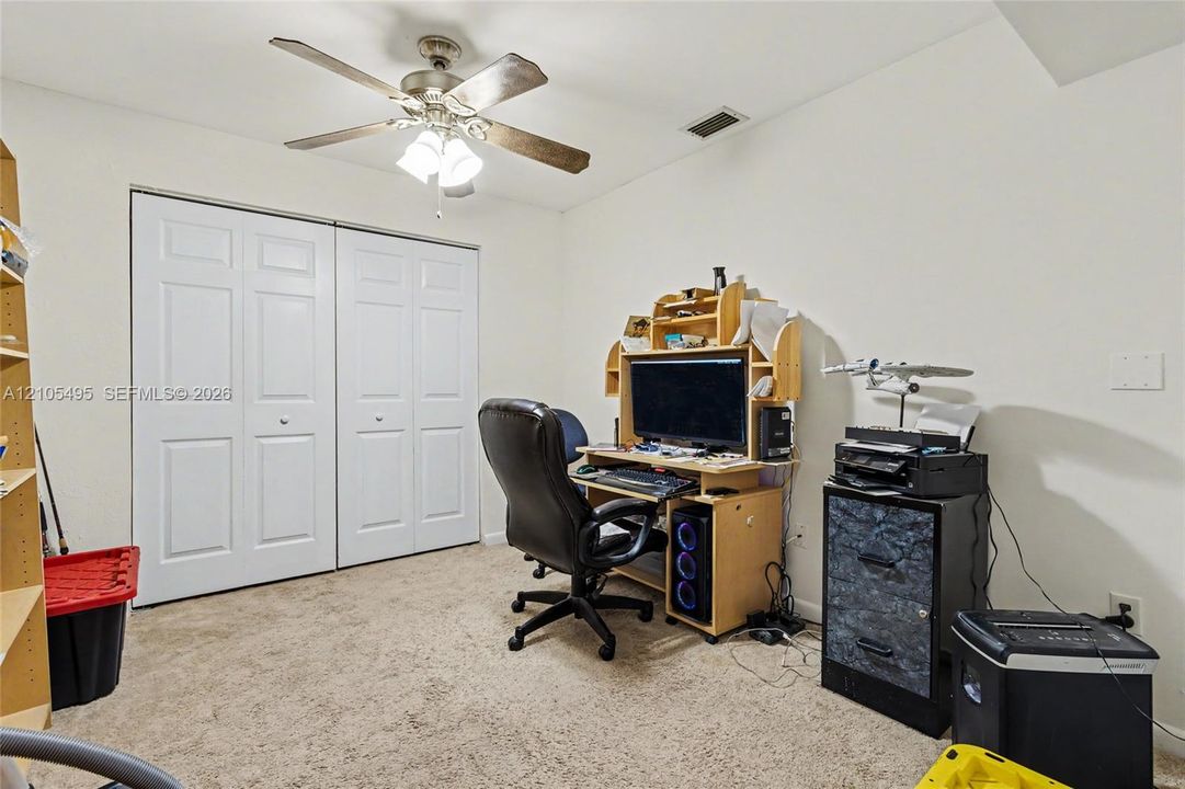Room featuring neutral carpeting, a ceiling fan with integrated lighting, and dual six-panel closet doors