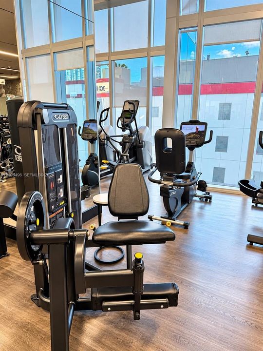 Fitness center featuring floor-to-ceiling windows, wood-finish flooring, and mirrored walls