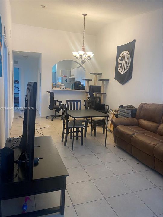 Vaulted ceiling, arched pass-through, tile flooring, recessed lighting, and a multi-light chandelier