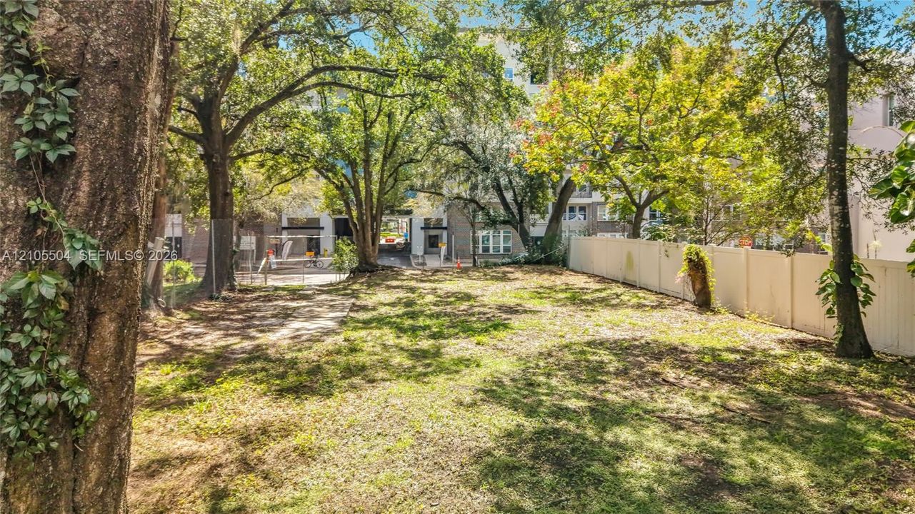 Expansive backyard featuring mature trees, partial privacy fencing, and open green space
