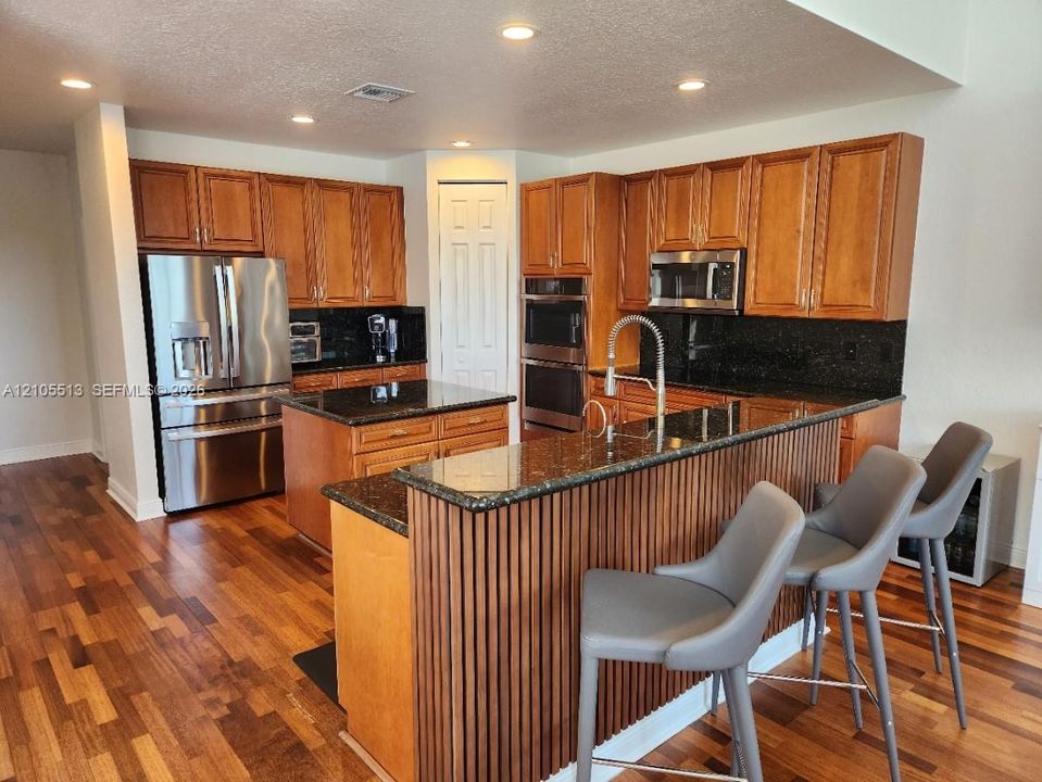 Solid maple wood cabinetry, new GE Profile appliances, dark granite countertops and recessed lighting