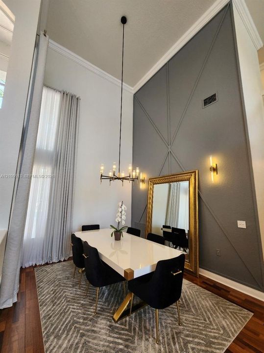 Dramatic 20ft accent wall with geometric molding, modern chandelier & wall sconces