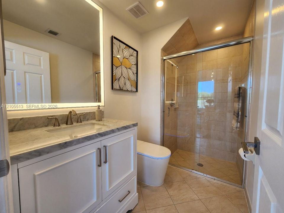 Guest Bathroom off main living areas w/modern vanity, marble sink top, lighted mirror & smart toilet