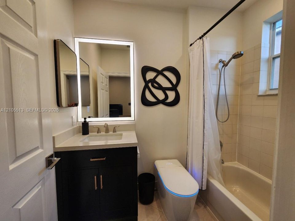 1st floor guest suite bathroom w/modern vanity, quartz sink top, lighted mirror & smart toilet